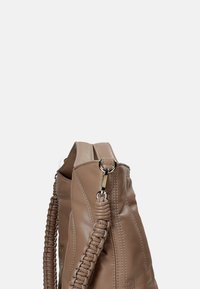 Borsa in pelle tan con dettagli intrecciati sulla maniglia, texture liscia, cuciture visibili e forma strutturata.