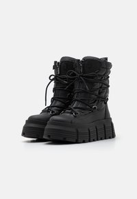 Black leather ankle boots with zipper and lace-up closure, featuring a chunky textured sole and padded shaft for added support.