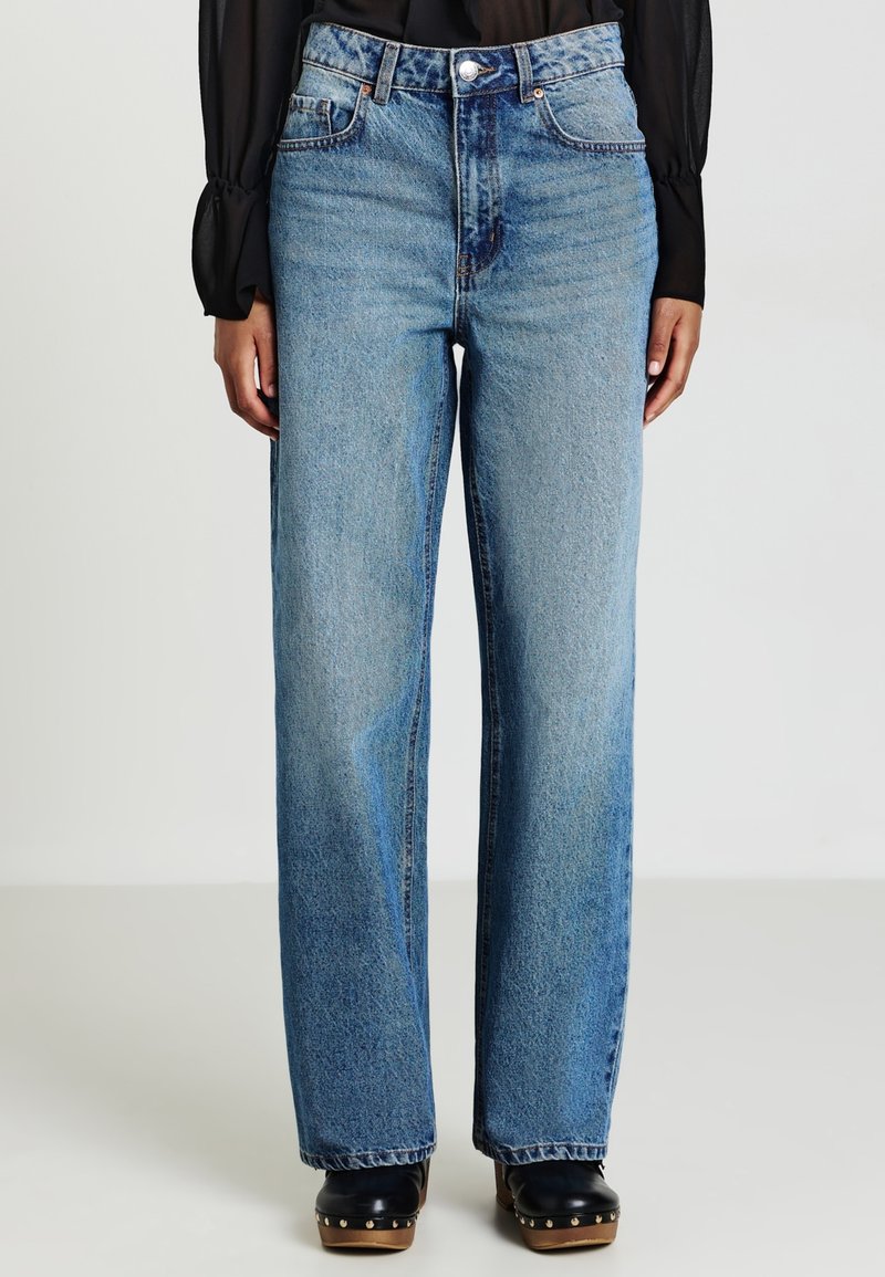 Hochgeschnittene, weit geschnittene Jeans in hellblauem Denim mit Knopfverschluss, fünf Taschen und einer leicht ausgeblichenen Textur.