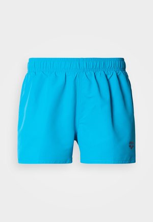 Turquoise swim shorts made of lightweight fabric, featuring an elastic waistband and a small black logo detail. Smooth texture, knee-length design.