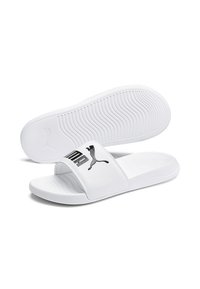 Vita sandaler i vitt med en bred rem som har en svart Puma-logotyp. Sulan har ett strukturerat greppmönster för bättre fäste.