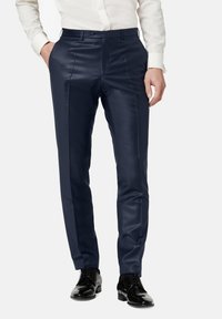 Marineblaues Hosen in einem glatten, glänzenden Stoff mit geradem Schnitt und Bügelfalte. Kombiniert mit schwarzen, glänzenden Halbschuhen.