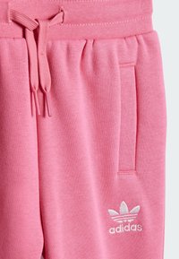 Rosa Adidas treningsbukser har en myk tekstur, justerbar livlinje med snor, sidelomme og hvit brodert logo.