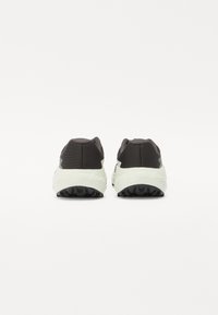 Baskets de sport gris foncé avec une tige texturée, une semelle intermédiaire blanche et une semelle extérieure en caoutchouc noir contrastante. Pas de logos ou de motifs visibles.