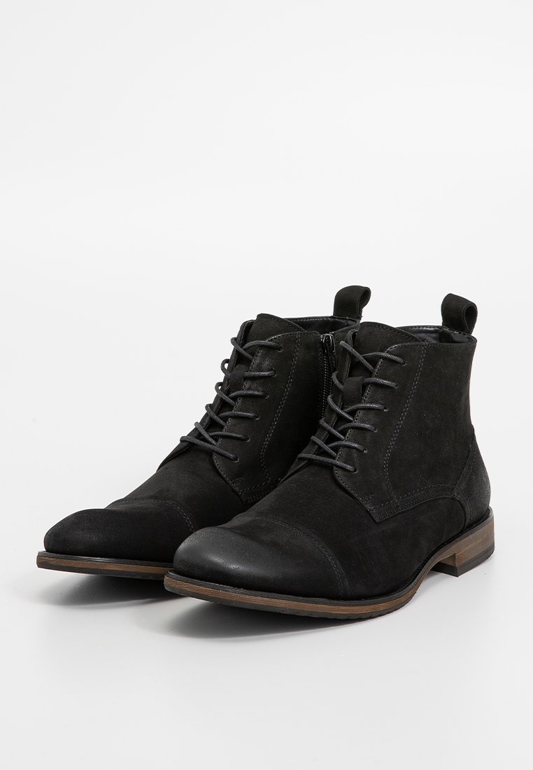 Schwarze Wildleder-Ankle-Boots mit runder Zehenpartie, Schnürung vorne, seitlichem Reißverschluss und flachem Holzabsatz. Strukturiertes Obermaterial mit glatten Lederelementen.