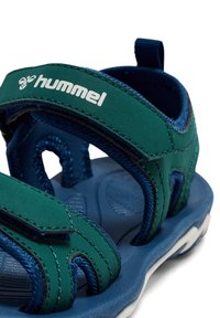 Sandały w kolorze morskim i granatowym z regulowanymi paskami, wykonane z materiału syntetycznego. Miękka wkładka i biała podeszwa z fakturą.