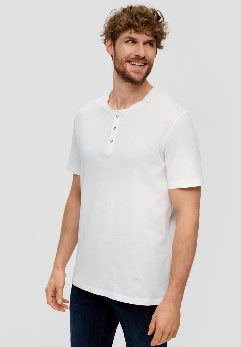 Weißes T-Shirt mit kurzen Ärmeln, das mit einem Henley-Ausschnitt und drei Knöpfen ausgestattet ist. Hergestellt aus weichem Baumwollstoff; reguläre Passform, glatte Textur.