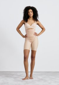 Kehutanga bodysuit me te hoahoa kua tapahia, i hangaia mai i te papanga maeneene, stretchy. Kei a ia nga rīngato whakarite me te roa i te pokanga waewae.