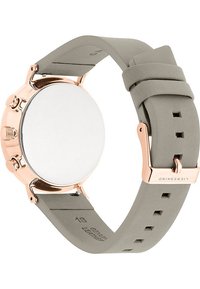 Rund klocka med ett hus i roséguld och ett slätt, grått läderarmband. Har tre knappar på sidan och en strukturerad spänne.