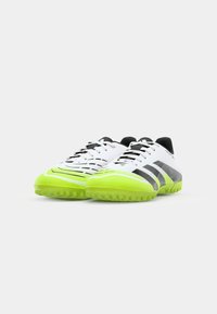 Chaussures de football avec une tige blanche, des accents noirs et une semelle verte éclatante. Design texturé et fermeture à lacets pour un maintien sécurisé.