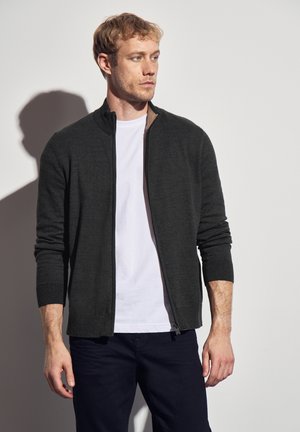 Donkergrijze ritssluiting cardigan met lange mouwen, slim fit, textuurstof en een contrasterende bruine kraag, gedragen over een wit T-shirt.