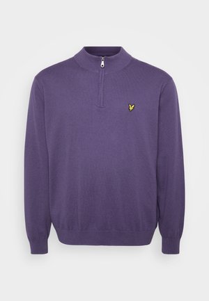 Maglione lavorato a maglia viola con colletto alto e zip a metà, caratterizzato da un piccolo logo giallo ricamato sul lato sinistro del petto. Tocco morbido.