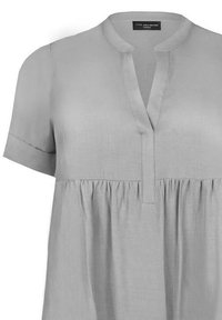 Světle šedá halenka s krátkým rukávem vyrobená z měkké látky. Má výstřih do V, sklady a volný střih. Obsahuje štítek na výstřihu.