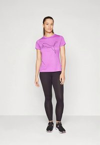 T-shirt viola a maniche corte con logo Puma nero, abbinata a leggings neri e scarpe da ginnastica nere con dettagli rosa.