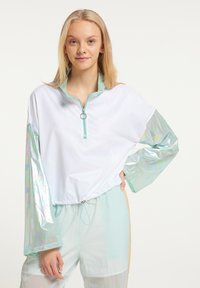 Let strikket hvid pullover i let materiale med mintgrønne detaljer, lange iriserende ærmer, lynlås lukning og justerbar kant med snoretræk.