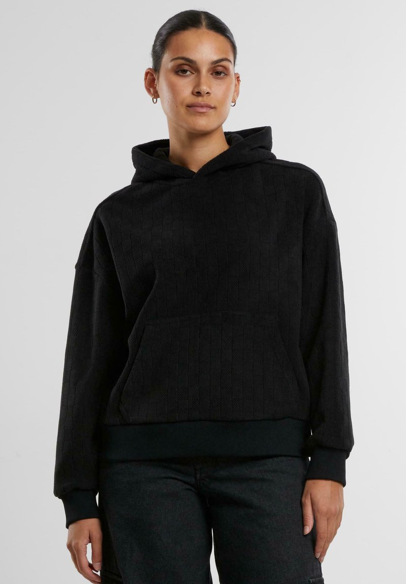 Felpa nera con cappuccio, caratterizzata da un motivo testurizzato, tasca a marsupio e polsini a costine. Il tessuto sembra morbido e caldo. Design cropped.