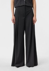 Spodnie o szerokich nogawkach w ciemnoszarym materiale, charakteryzujące się wyraźnymi plisami, wysokim paskiem i dopasowanym krojem. Gładka faktura z delikatnym połyskiem.