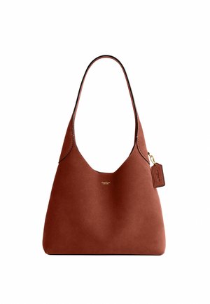 Sac à épaule Coach en cuir marron avec une bandoulière simple et un petit logo doré ainsi qu'une étiquette sur le côté.