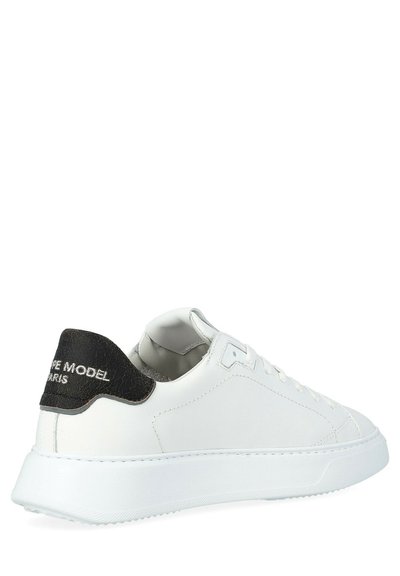 Sneaker bianco in pelle con un accento sul tallone nero testurizzato. Presenta una punta arrotondata, lacci piatti e una suola in gomma con un motivo a ondulazione.