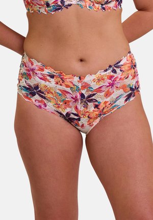 Mujer vistiendo un conjunto de lencería de encaje floral con bragas de cintura alta, que presenta patrones de flores de colores naranja, rosa, púrpura y verde azulado sobre tela blanca.