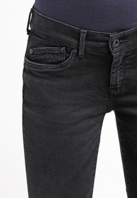 Czarne dżinsy o slim fit, pięciokieszeniowym wzornictwie oraz zapięciu na guzik, z subtelnym logo na przedniej kieszeni.