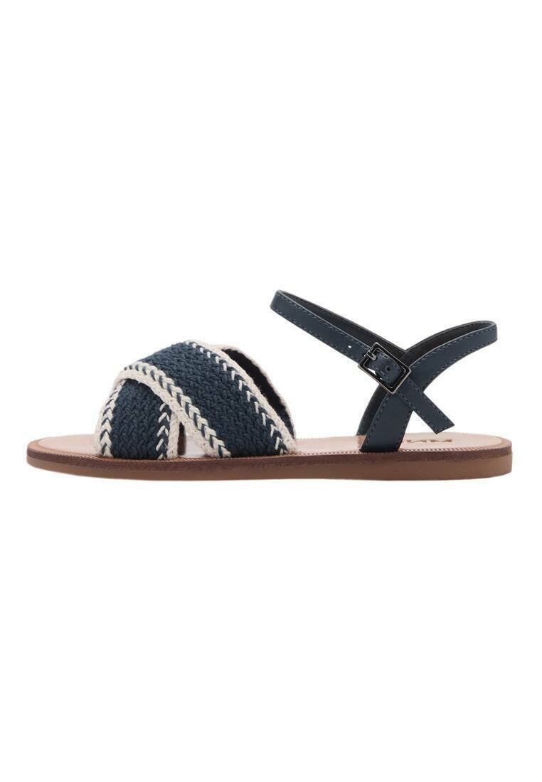 Sandali intrecciati blu navy e crema con design a strap incrociato, cinturino alla caviglia regolabile e suola piatta marrone.