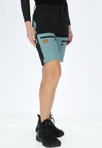 Pantaloni corti a più tasche neri e teal, con vita elastica e dettagli con cerniera su ogni tasca. Adatti per attività all'aperto.