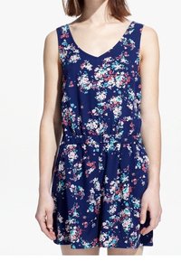 Květinový overal v tmavě modré tkanině s výstřihem do V. Má elastický pas a barevné květinové vzory v růžové a tyrkysové barvě.