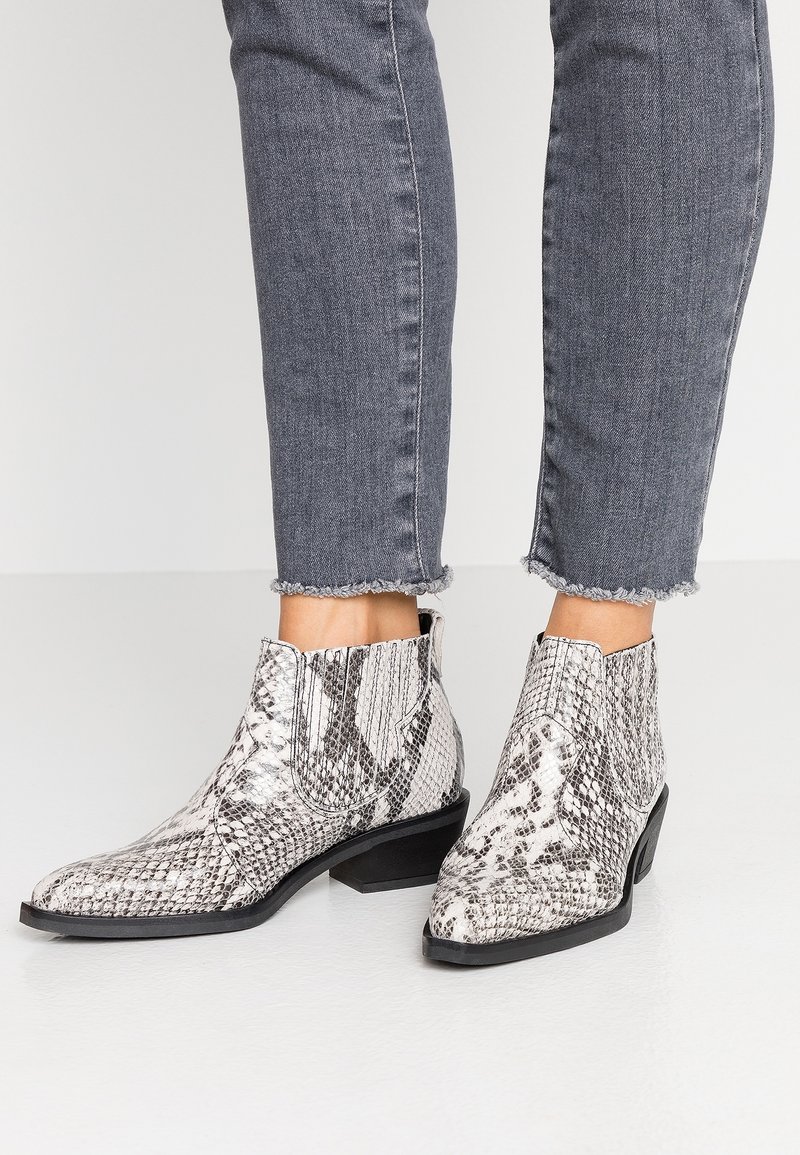 Schwarz-weiße Schlangenleder-Print Stiefeletten mit niedrigem, gestapeltem Absatz, spitzem Schuh und plissierten Details an den Seiten.