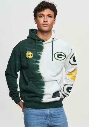 Hoodie avec un design divisé ; côté gauche vert foncé, côté droit blanc. Comprend des logos verts et dorés, un cordon de serrage ajustable et une poche frontale.