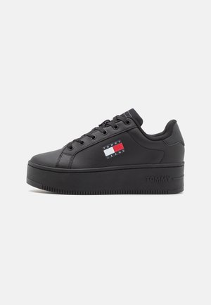 Czarny sneaker na platformie z sznurowaniem z przodu, wyściełanym kołnierzem i flagą z logo Tommy Jeans z boku.