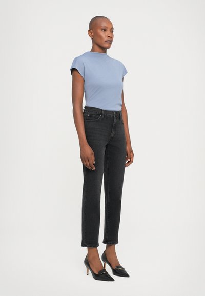 Lys blå kortermet topp, svarte høytlivsjeans og svarte spisse hæler. Enkel design med en glatt tekstur og minimal detaljering.