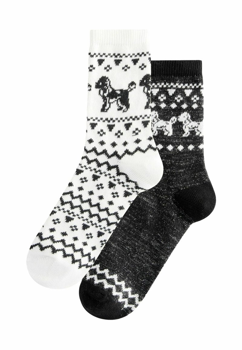 Stricksocken, eine weiß mit schwarzem Hund und geometrischen Mustern, die andere schwarz mit weißen Mustern und kleinen Hundedetails.