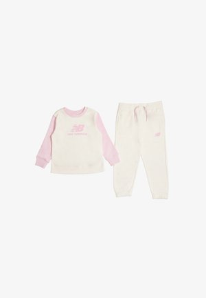 Tuta per bambini in due pezzi con felpa dal corpo crema e maniche rosa, pantaloni della tuta crema abbinati, entrambi con loghi New Balance rosa.