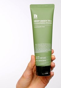 Tube vert et compressible de Benton Deep Green Tea Cleansing Foam avec une base noire, texte en relief, capuchon à charnière et design minimaliste.