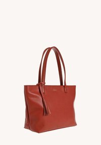 Sac fourre-tout en cuir rouge avec une surface texturée, deux longues poignées et un détail en pompon. Présente un design structuré et un haut ouvert.