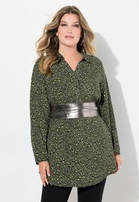 Tunic nera con stampa leopardata gialla e verde, maniche lunghe, colletto e una cintura metallica argento in vita. Tessuto dalla superficie liscia.