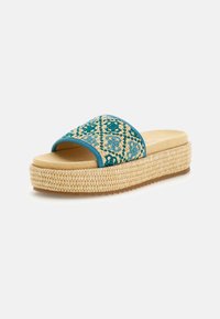 Woven slide sandal with teal patterned strap, natural rope midsole, flat sole, and light beige footbed. Simple, casual design.