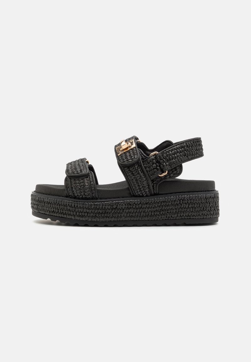 Sandali platform neri con cinturini intrecciati, fibbie regolabili e una suola spessa e texturizzata per grip e stabilità. Design minimalista.