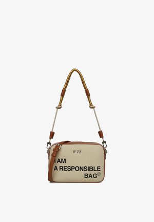 Sac bandoulière rectangulaire beige avec garniture en cuir marron, poignée tissée jaune et noire, et texte noir indiquant "JE SUIS UN SAC RESPONSABLE."