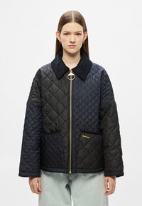 Μαύρο καπιτονέ μπουφάν με κοντινή αντίθεση, χρυσό φερμουάρ και πλαϊνές τσέπες. Διαθέτει διακριτικό χρυσό λογότυπο στην αριστερή τσέπη.