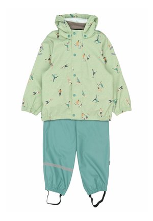 Grøn vandtæt jakke med legende fodboldspillerprint, kombineret med turkis bukser med reflekterende stribe og justerbare elastiske manchetter.