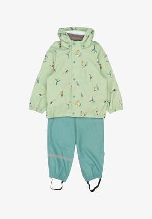 Zelena vodootporna jakna s razigranim tiskom nogometaša, uparena s tirkiznim hlačama koje imaju reflektirajući prsten i podesive elastične manžete.