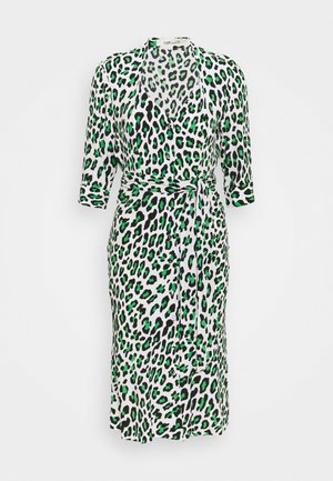 Biała sukienka kopertowa do kolan z czarnym i zielonym nadrukiem w cętki, z rękawami o długości do łokcia oraz paskiem z tej samej tkaniny związanym w talii.