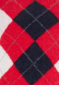 Gyapjú keverékanyag piros, fekete és fehér argyle mintázattal, amely puha textúrával rendelkezik, és a gyémánt formákat finom varrással keretezik.