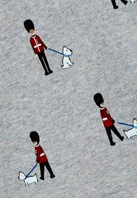 Tessuto grigio con un motivo di guardie in uniformi rosse che portano cani bianchi al guinzaglio blu, con dettagli neri e marroni.