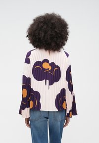 Világos rózsaszín redős blúz lila és narancssárga virágmintákkal, hátul kulcslyuk alakú kivágással és bővülő ujjakkal.