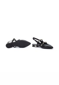Zapatos negros de cuero tipo slingback con punta puntiaguda, tiras anchas que presentan acentos metálicos y un tacón bajo cuadrado con una suela texturizada.