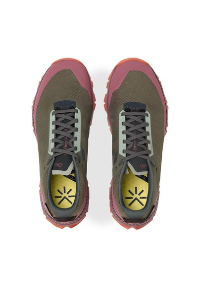 Une paire de baskets vertes et roses à lacets avec des semelles intérieures jaunes et des logos noirs en forme d'étoile, vues de dessus sur un fond blanc.
