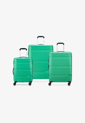 Drie groene koffers in verschillende maten, gemaakt van hard plastic, met gestructureerde oppervlakken, zwarte handvatten en elk vier draaibare wielen.